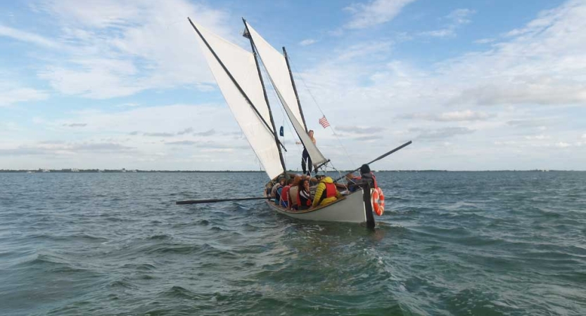 A sailboat holding a group of people floats on the water.